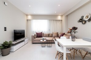A modern living room with a sofa, TV, and dining area. - Selozia Apartment (Zakynthos)