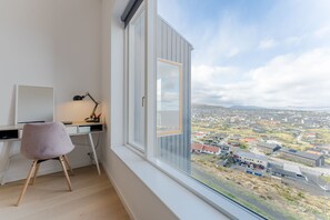 A modern room with a large window, a desk, a chair, and a lamp. - Sea & City View - Luxurious - Hiking (Argir)