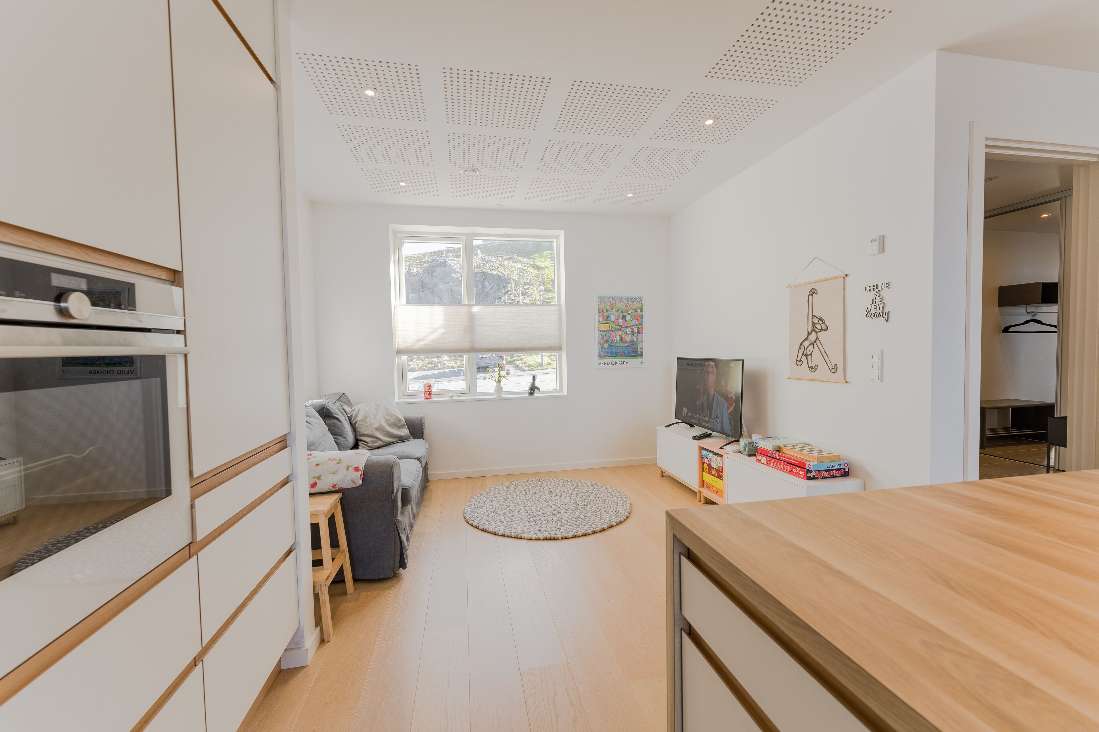 Una cocina moderna con horno empotrado, una zona de comedor con mesa de madera y un rincón de estar acogedor con sofá y alfombra.