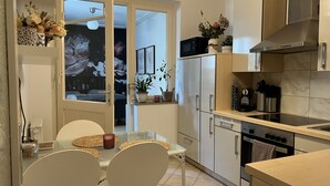 A modern kitchen with a dining area, featuring a glass table, white chairs, a coffee machine, and a microwave. - Schöne Ruhige Zentrale Designerwohnung (Hannover)
