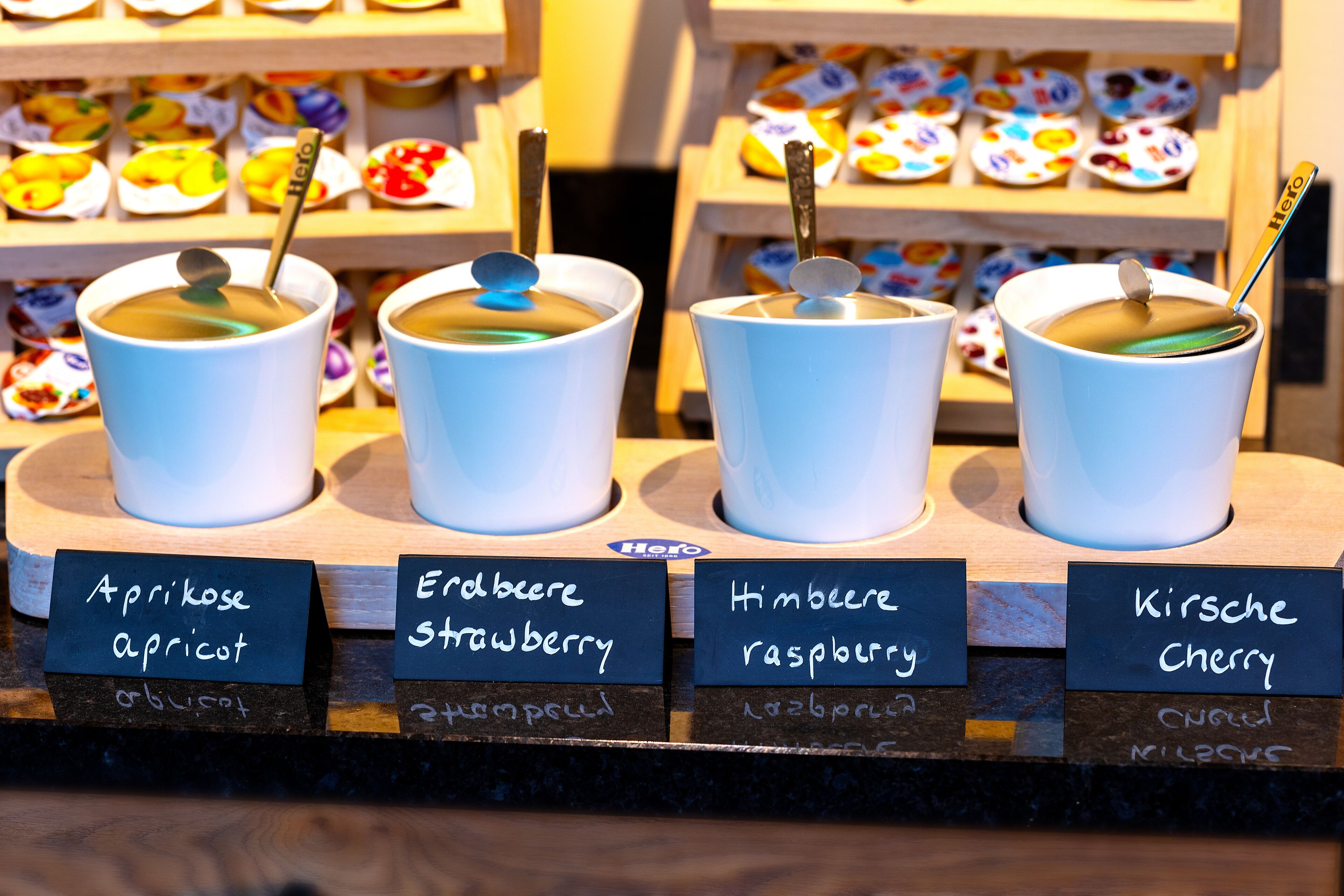Four cups of tea with different labels indicating flavors such as apricot, strawberry, raspberry, and cherry.