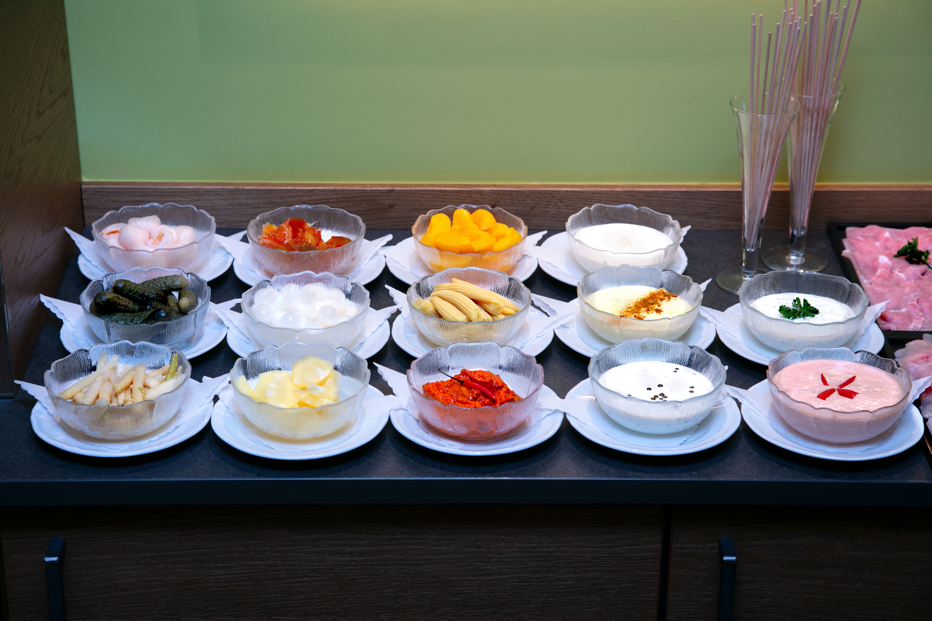 Una mesa de buffet con diversos alimentos y condimentos dispuestos en platos.