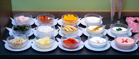 Una mesa de buffet con diversos alimentos y condimentos dispuestos en platos.