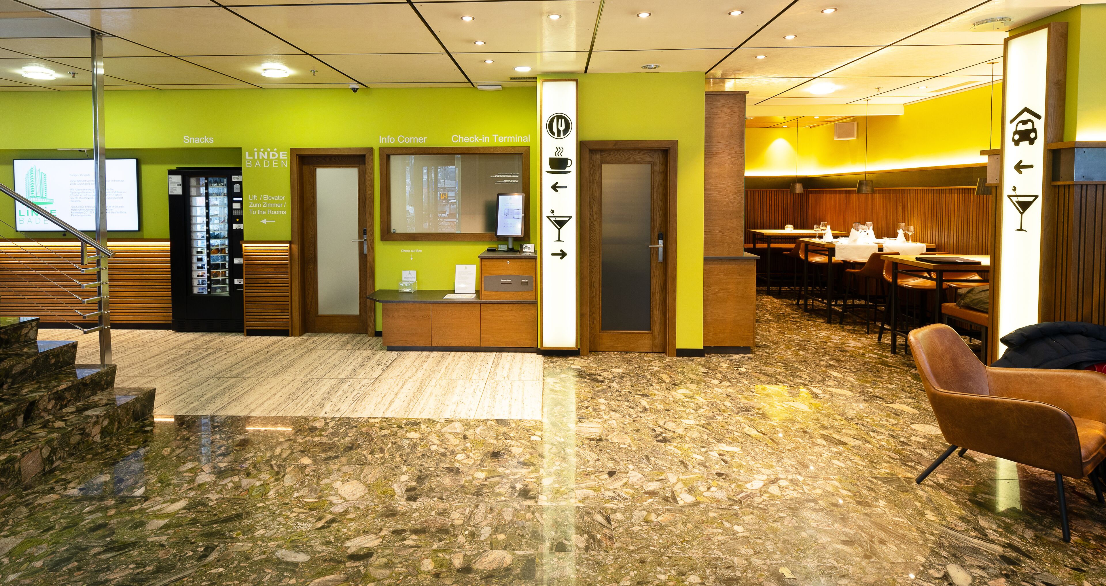 Eine Hotelhalle mit einer Rezeption, einer Sitzecke und Hinweisschildern.