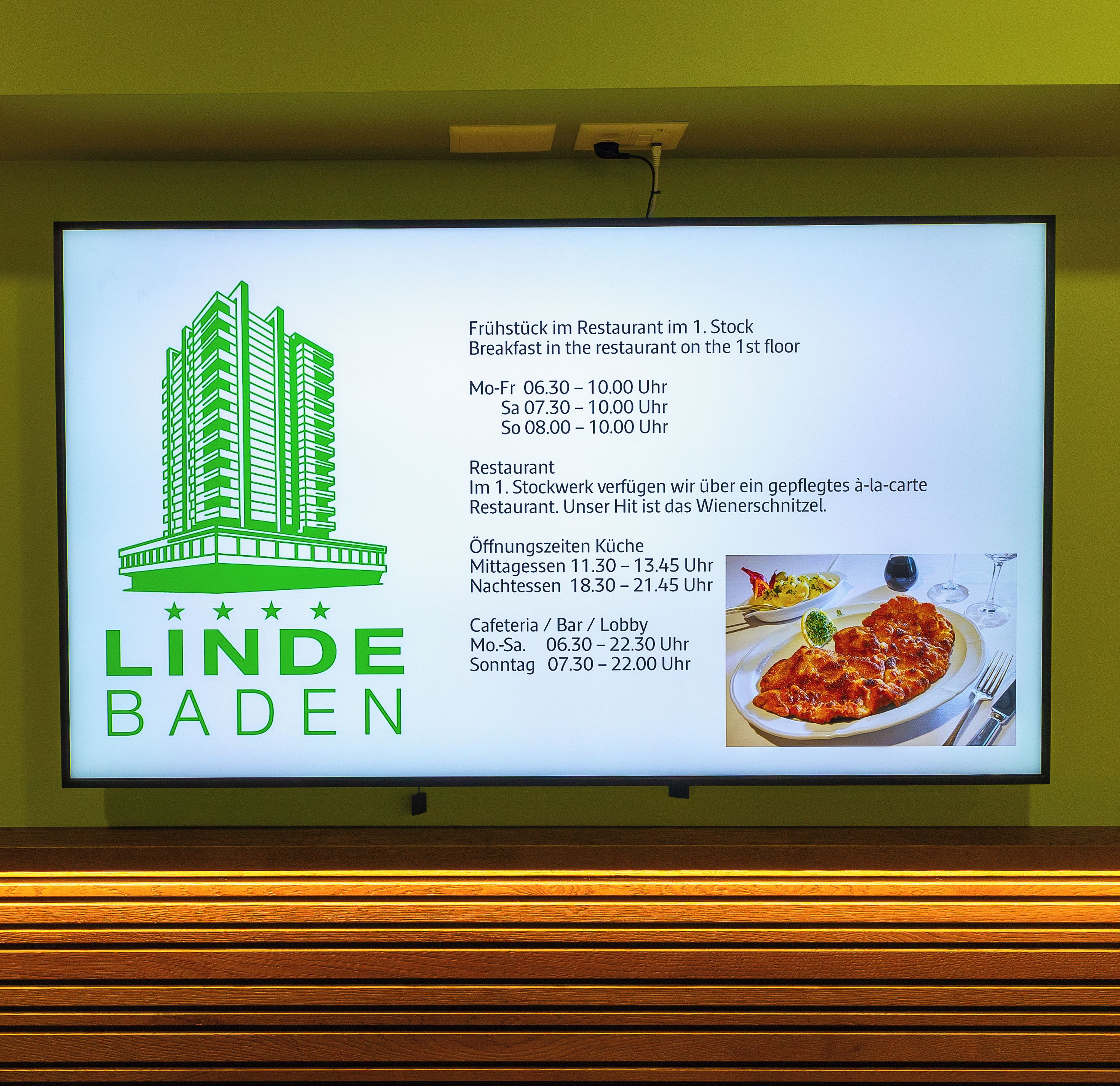 A signboard with the logo of 'LINDE BADEN' and details of restaurant hours and locations.