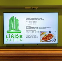 Uma placa de sinalização com o logotipo 'LINDE BADEN' e informações sobre horários e localização do restaurante.