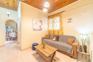 A living room with a sofa, a coffee table, a lamp, and a painting on the wall. - Holiday Home "Corfu House in River" with Garden & Wi-Fi (Kerkyra)