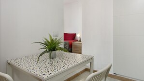 A small room with a white table, a potted plant, a red pillow, and a bedside lamp. - Vacation Home "Massimo Tipo 2" with Mountain View, Terrace & Wi-Fi (Las Palmas de Gran Canaria)