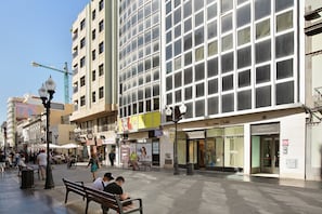 Une rue animée en ville, bordée de boutiques, de bancs et d’un trottoir pour les piétons.
