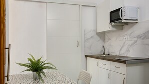 A compact kitchen with a microwave, a sink, and a potted plant on a tiled table. - Vacation Home "Massimo Tipo 2" with Mountain View, Terrace & Wi-Fi (Las Palmas de Gran Canaria)