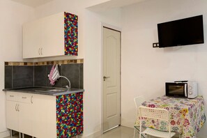 Une cuisine compacte équipée d’un four à micro-ondes, d’un évier et d’un meuble avec un revêtement mural aux couleurs vives.