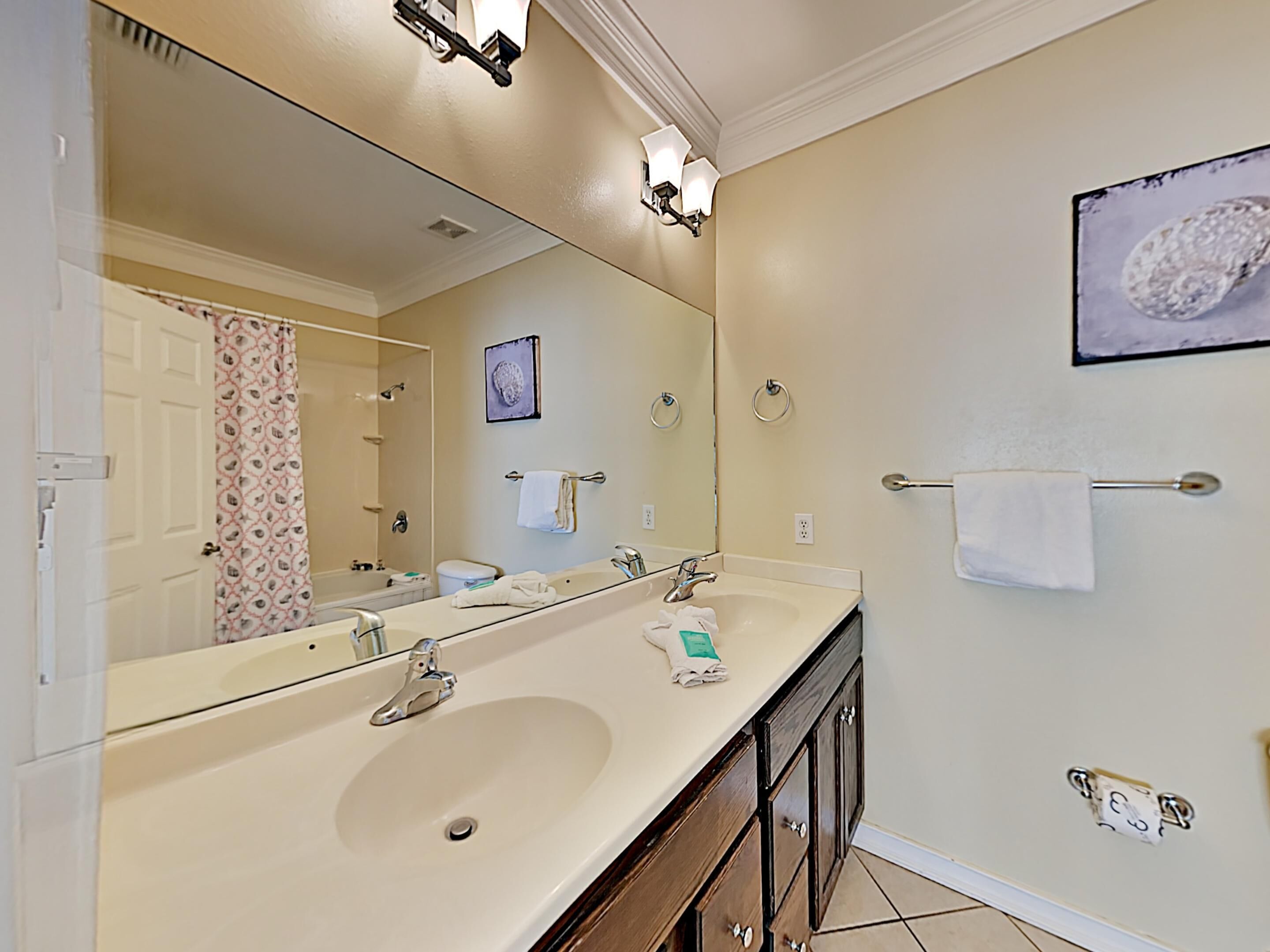 Une salle de bain avec un double lavabo, un grand miroir et un porte-serviettes.