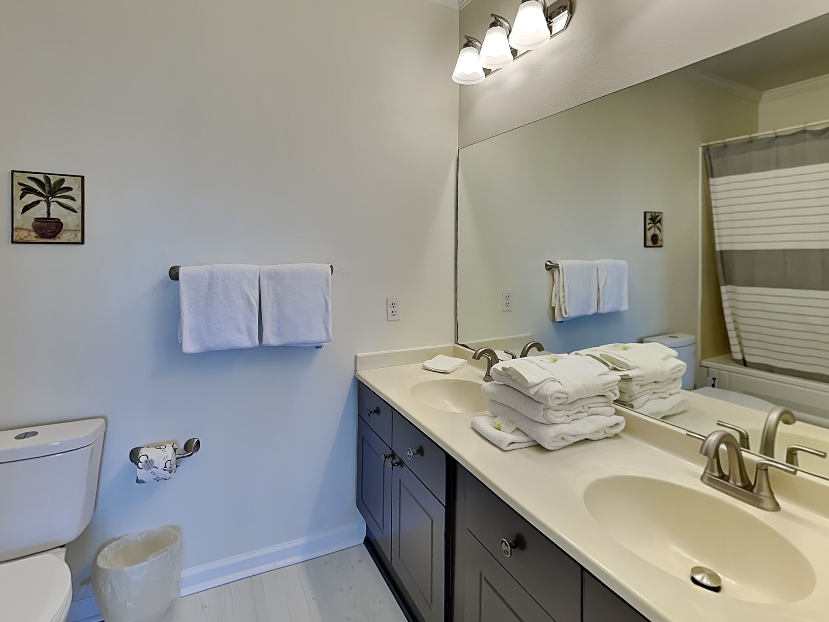 A bathroom with a white sink, two towel racks, a toilet, and a mirror.