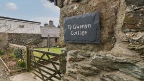 Una cabaña de piedra con un letrero que dice "Ty Gwyn Cottage".