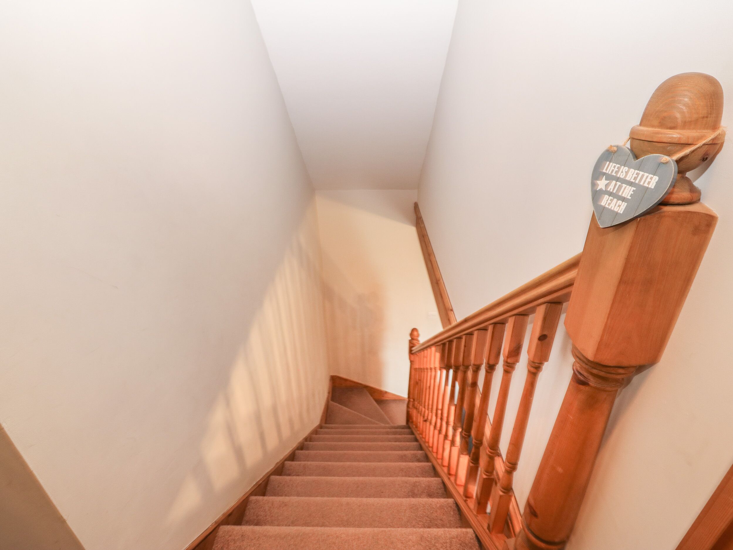 A wooden staircase with a handrail and a sign that reads "Life is better at the beach."