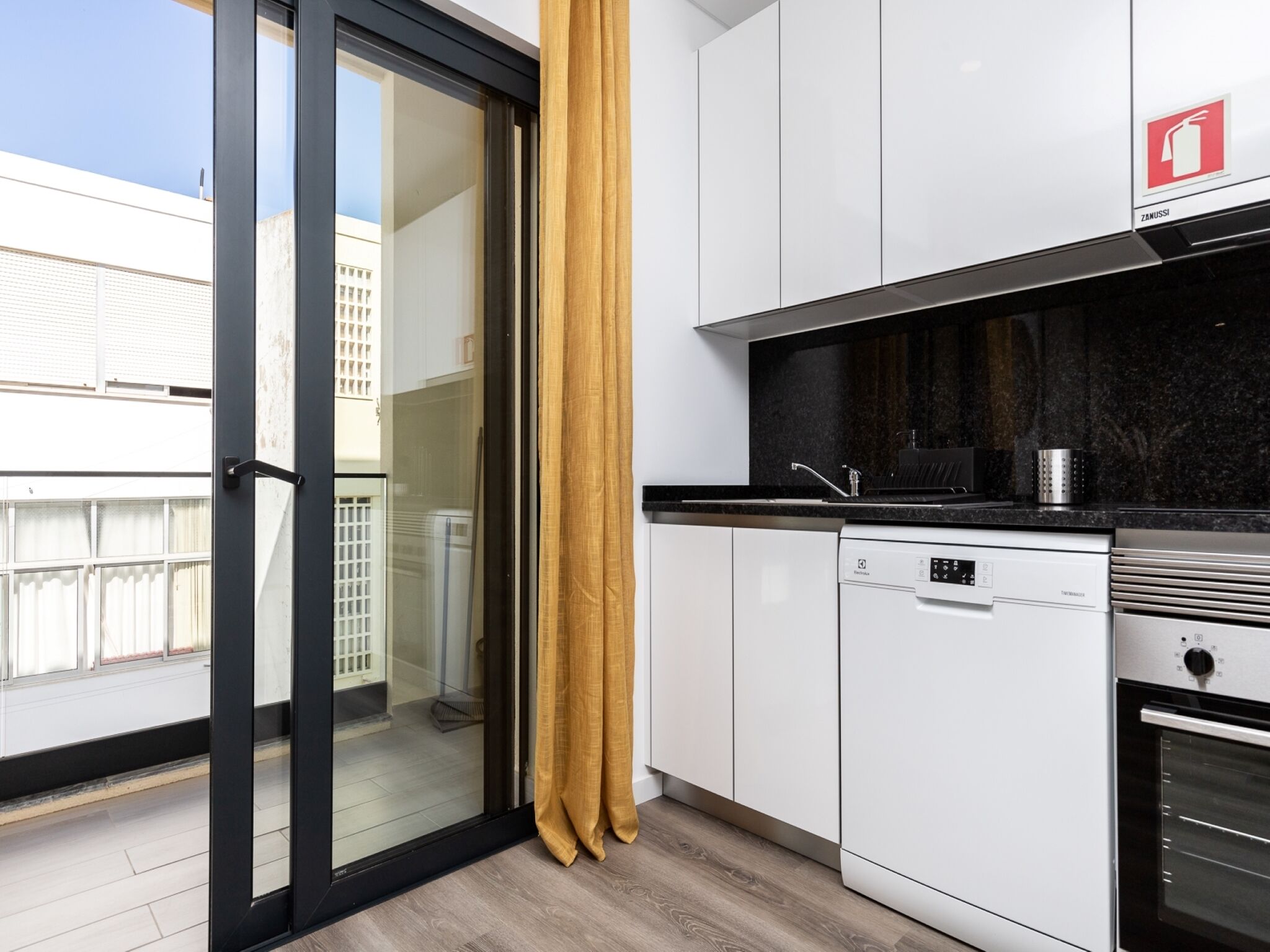 A modern kitchen with white cabinets, a black countertop, and stainless steel appliances.