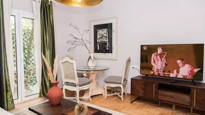 Un salon comprenant un téléviseur, une table à manger, des chaises, un vase et une plante décorative.