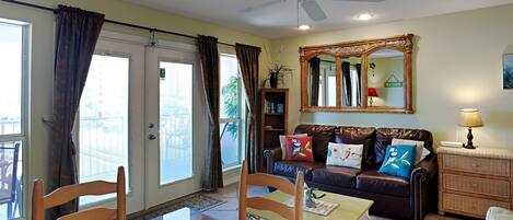 Una sala de estar con una mesa de comedor, sillas, un sofá, un ventilador de techo, un espejo y una lámpara.