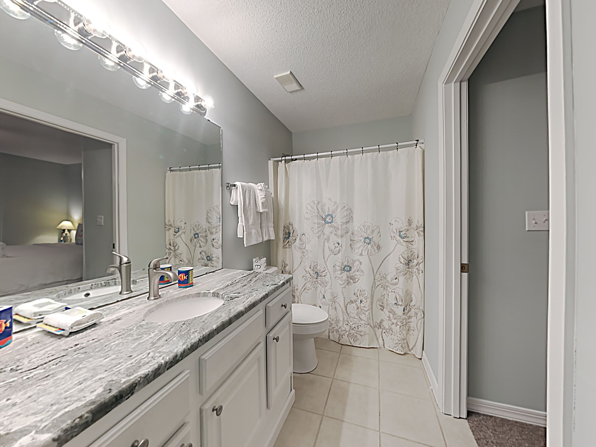 A bathroom with a marble sink, a toilet, and a shower curtain with floral patterns.