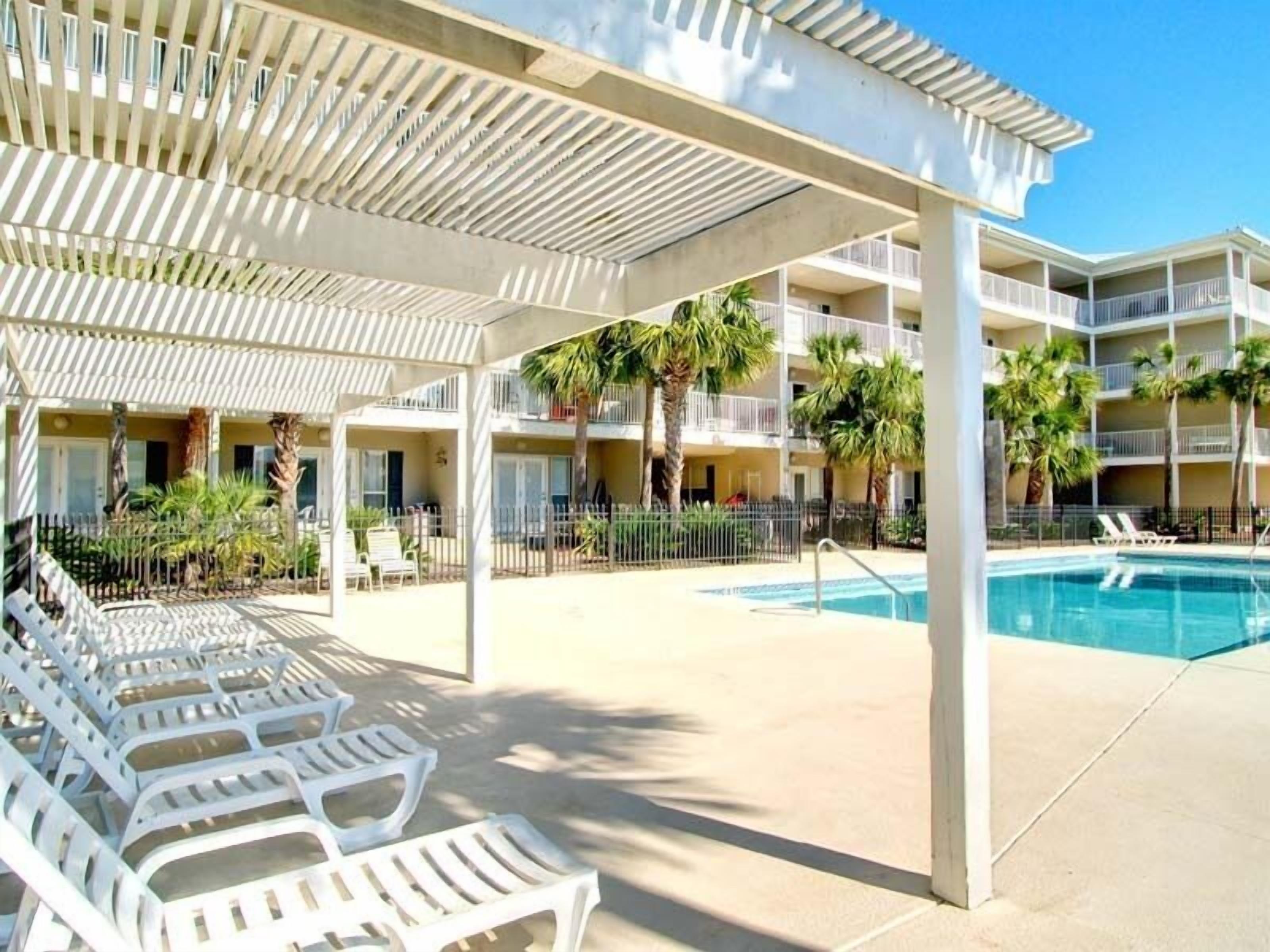 A hotel with a pool area, outdoor seating, and palm trees.