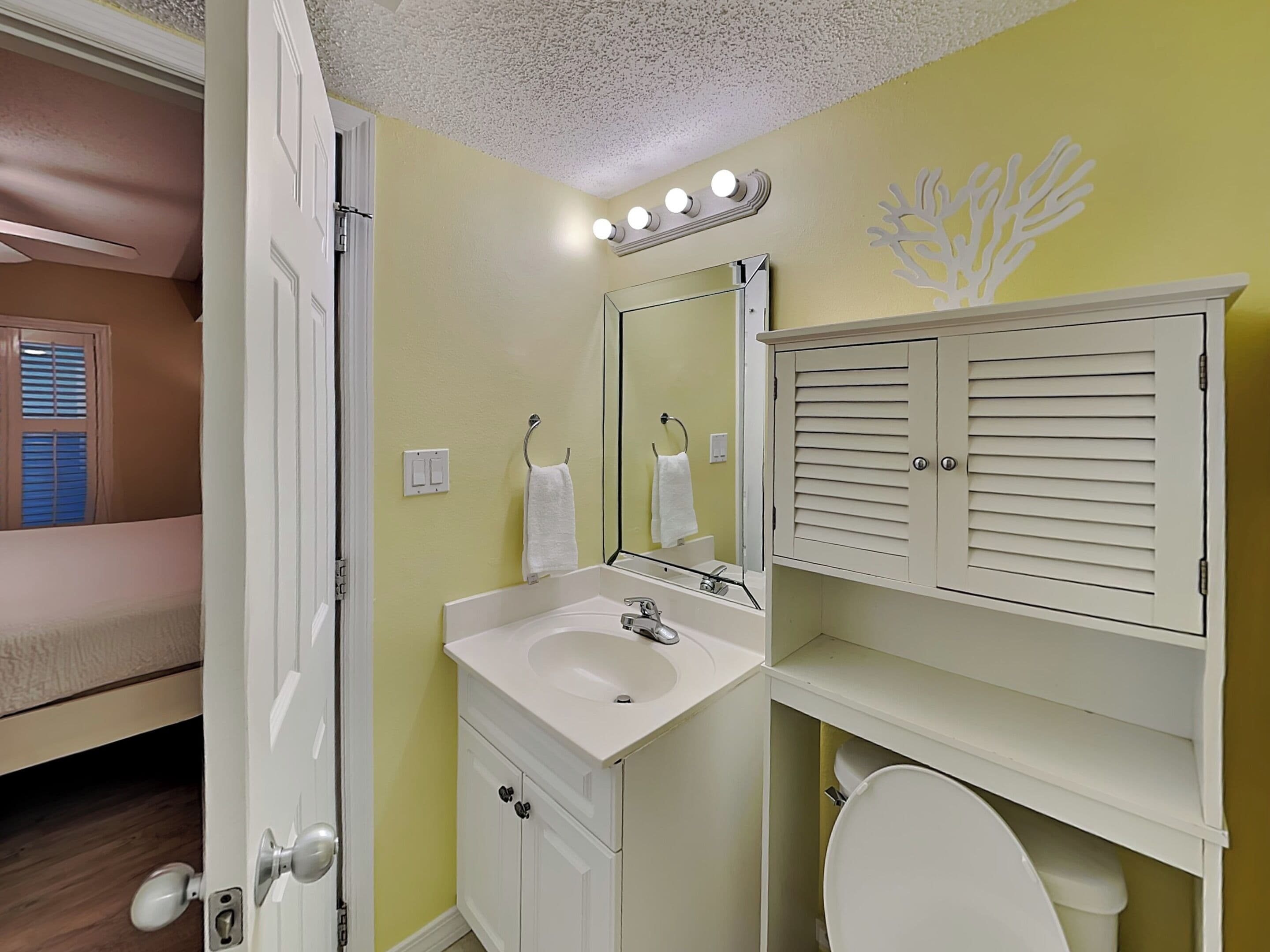 Un baño con lavabo, espejo e inodoro.