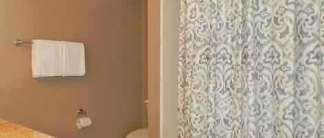 A bathroom with a marble sink, a toilet, and a patterned shower curtain.