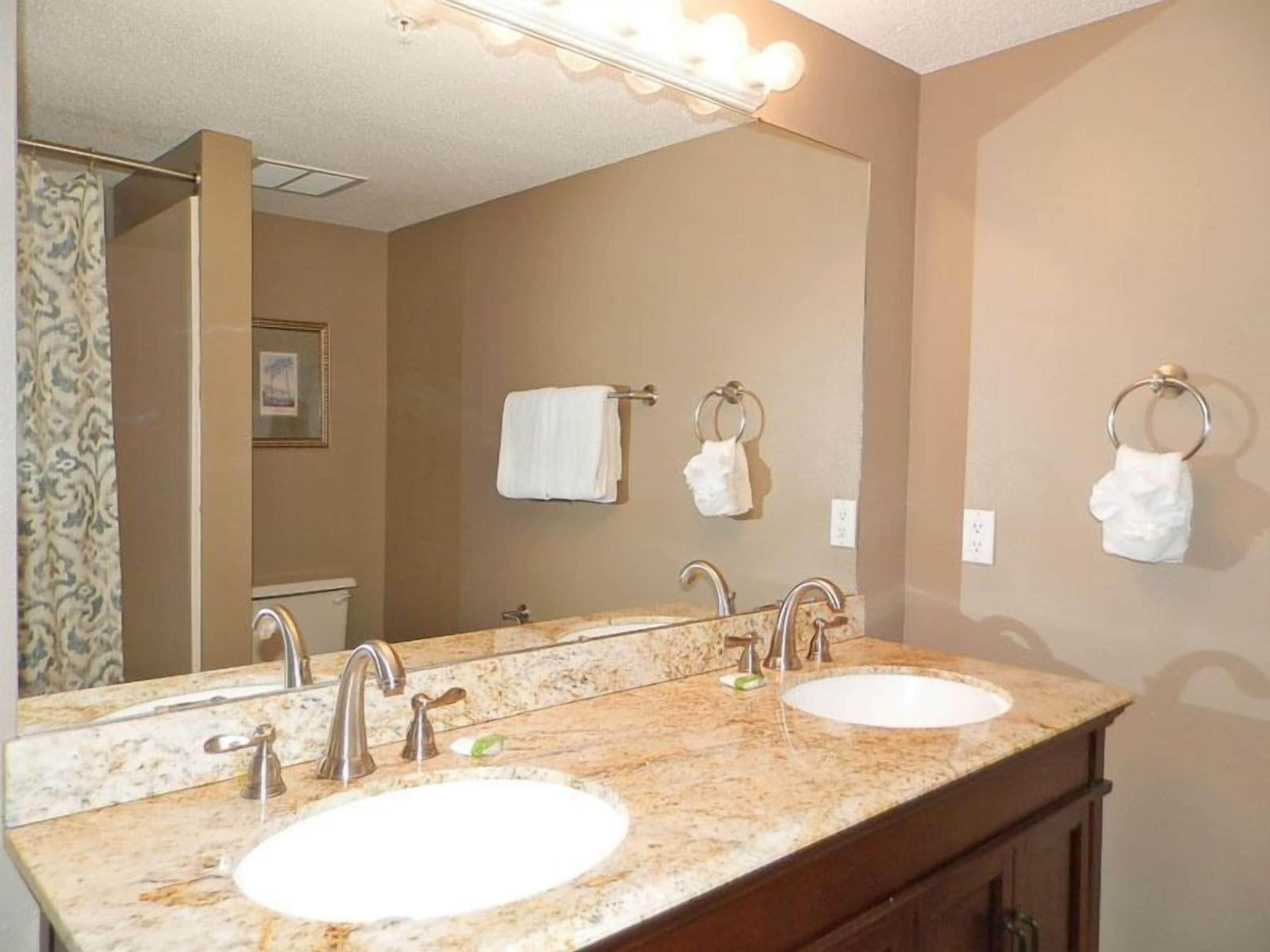 A bathroom with a double sink, two mirrors, and a vanity with a cabinet.