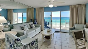 Ein Wohnzimmer mit Sofa, Sessel, Couchtisch und Meerblick durch große Fenster.