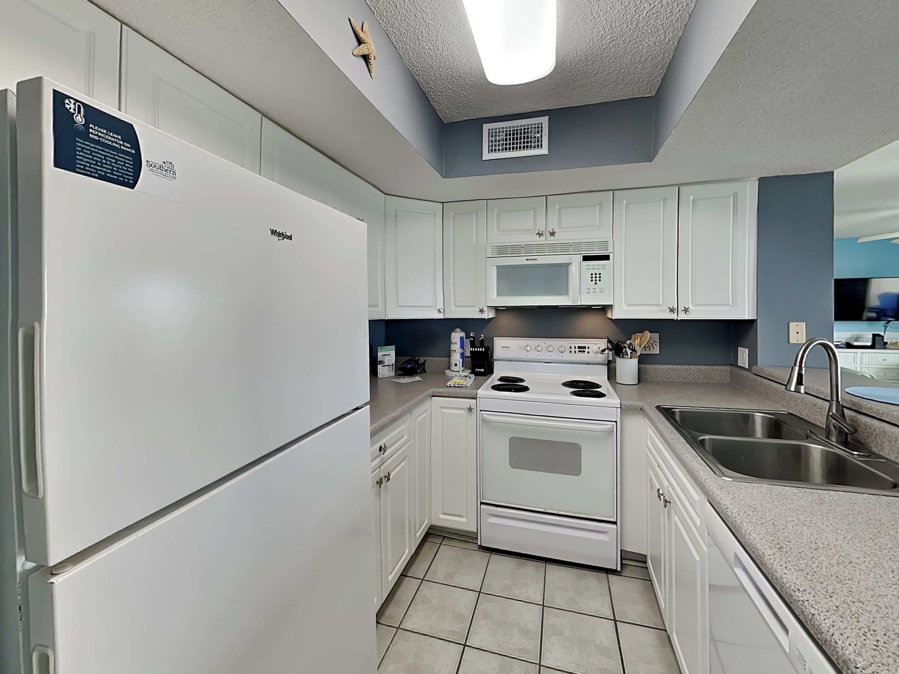 A compact kitchen with white cabinetry, a built-in microwave, a stove, and a sink.