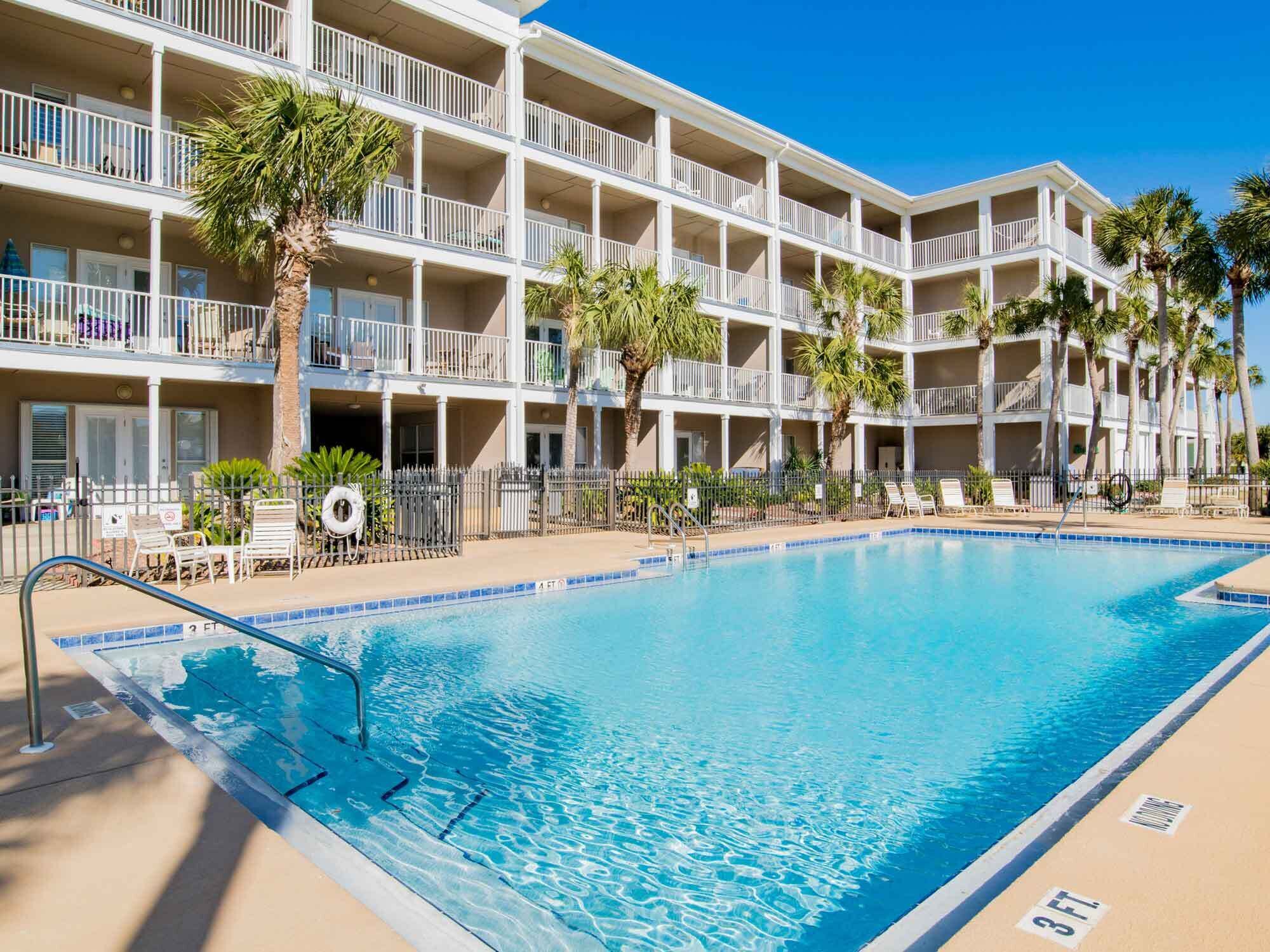 Un hôtel doté d’une piscine, de plusieurs balcons et de palmiers.