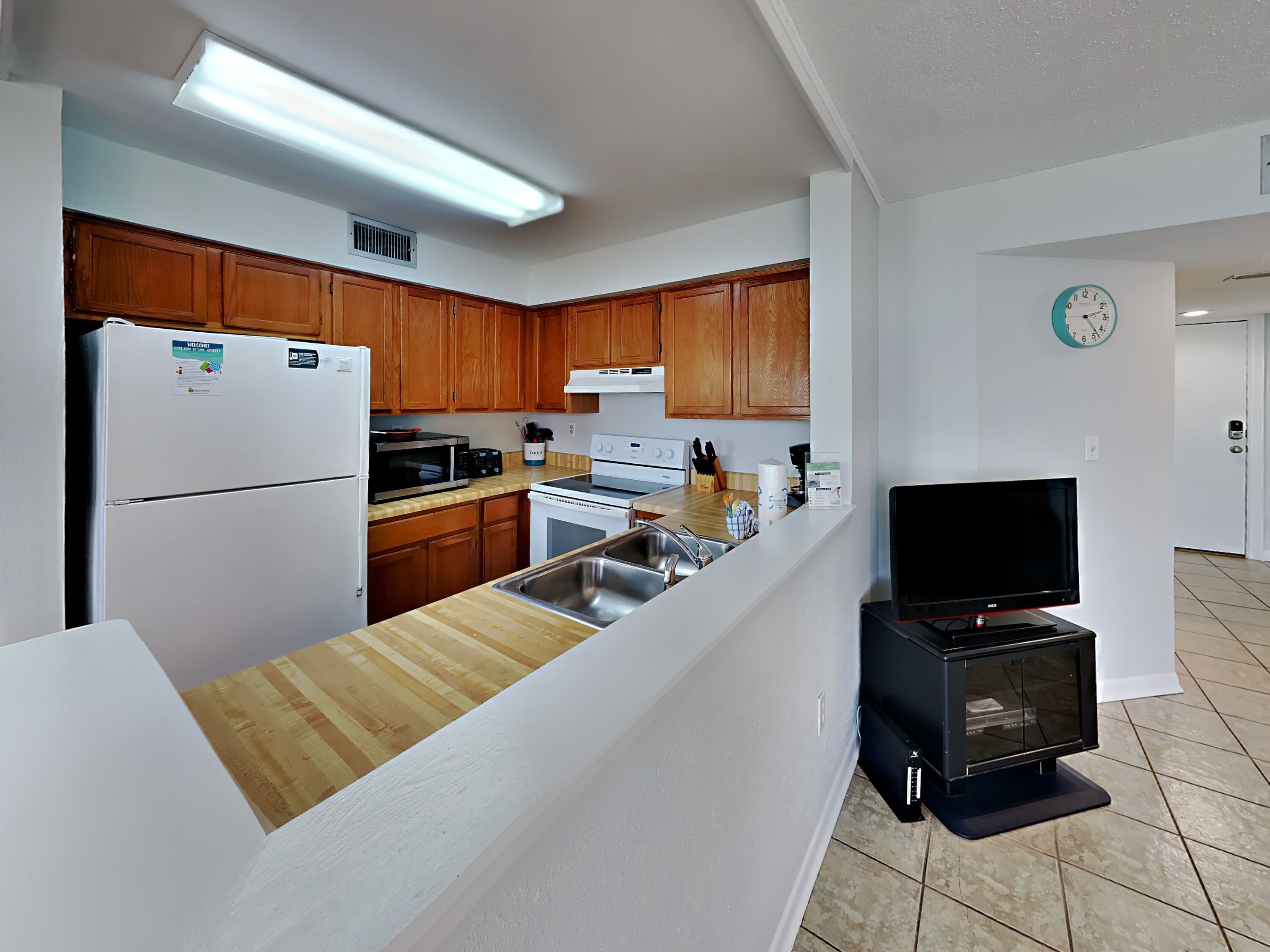 A modern kitchen with wooden cabinets, a refrigerator, microwave, stove, and a built-in oven.