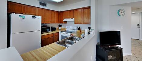 A modern kitchen with wooden cabinets, a refrigerator, microwave, stove, and a built-in oven.