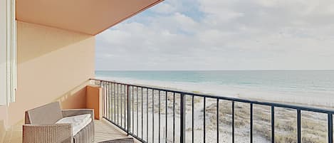 Un balcón con muebles de mimbre que da a una playa.
