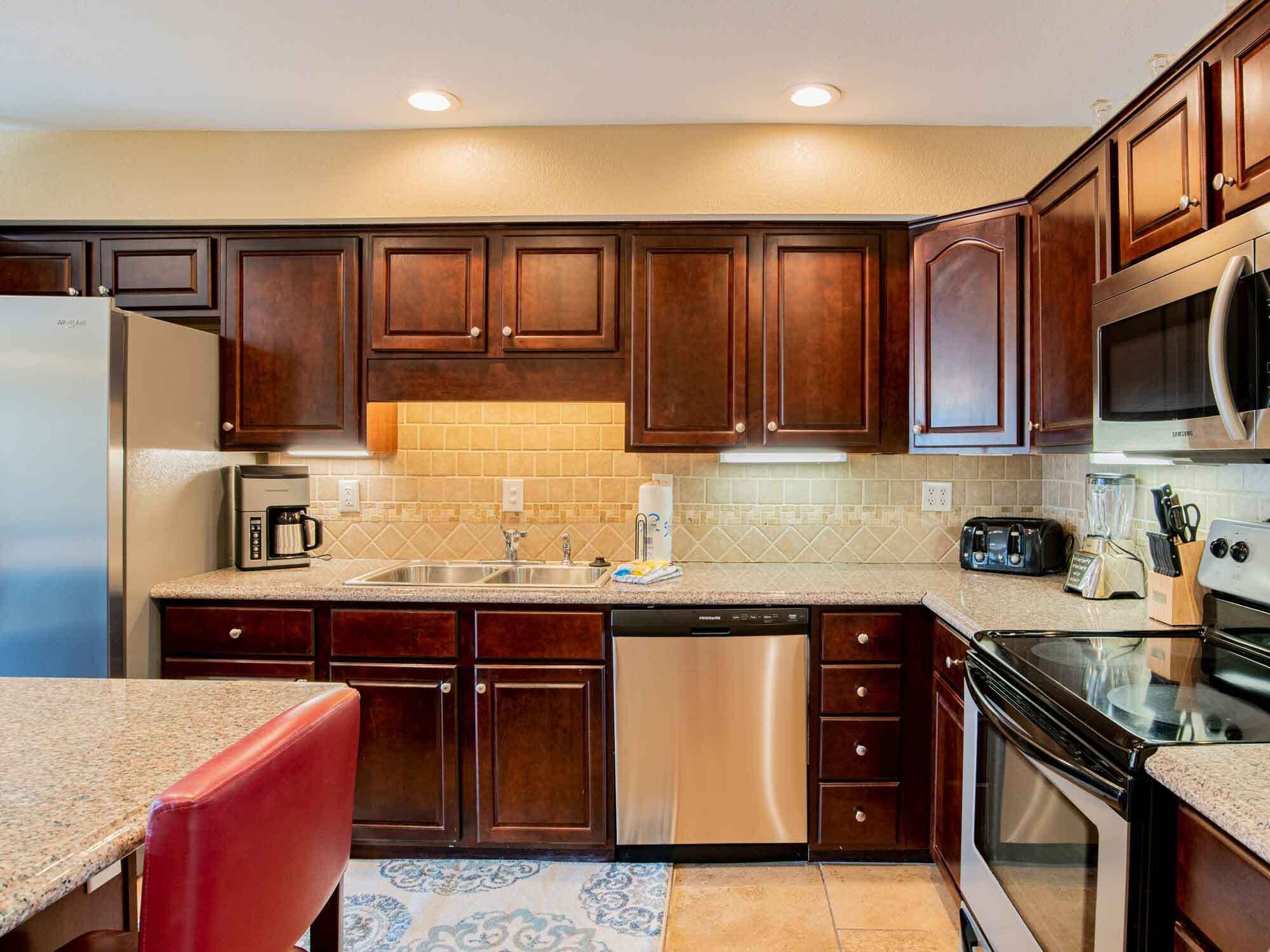 Una cocina con armarios de madera oscura, electrodomésticos de acero inoxidable y encimera de granito.