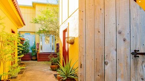 A narrow alleyway with potted plants and a wooden door.
