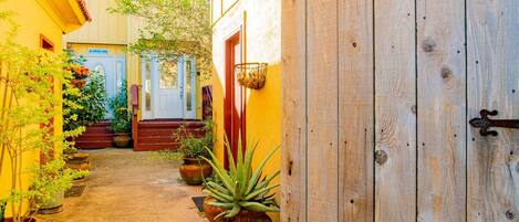 A narrow alleyway with potted plants and a wooden door.