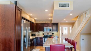 A modern kitchen with dark wood cabinets, stainless steel appliances, and a central island with red bar stools.