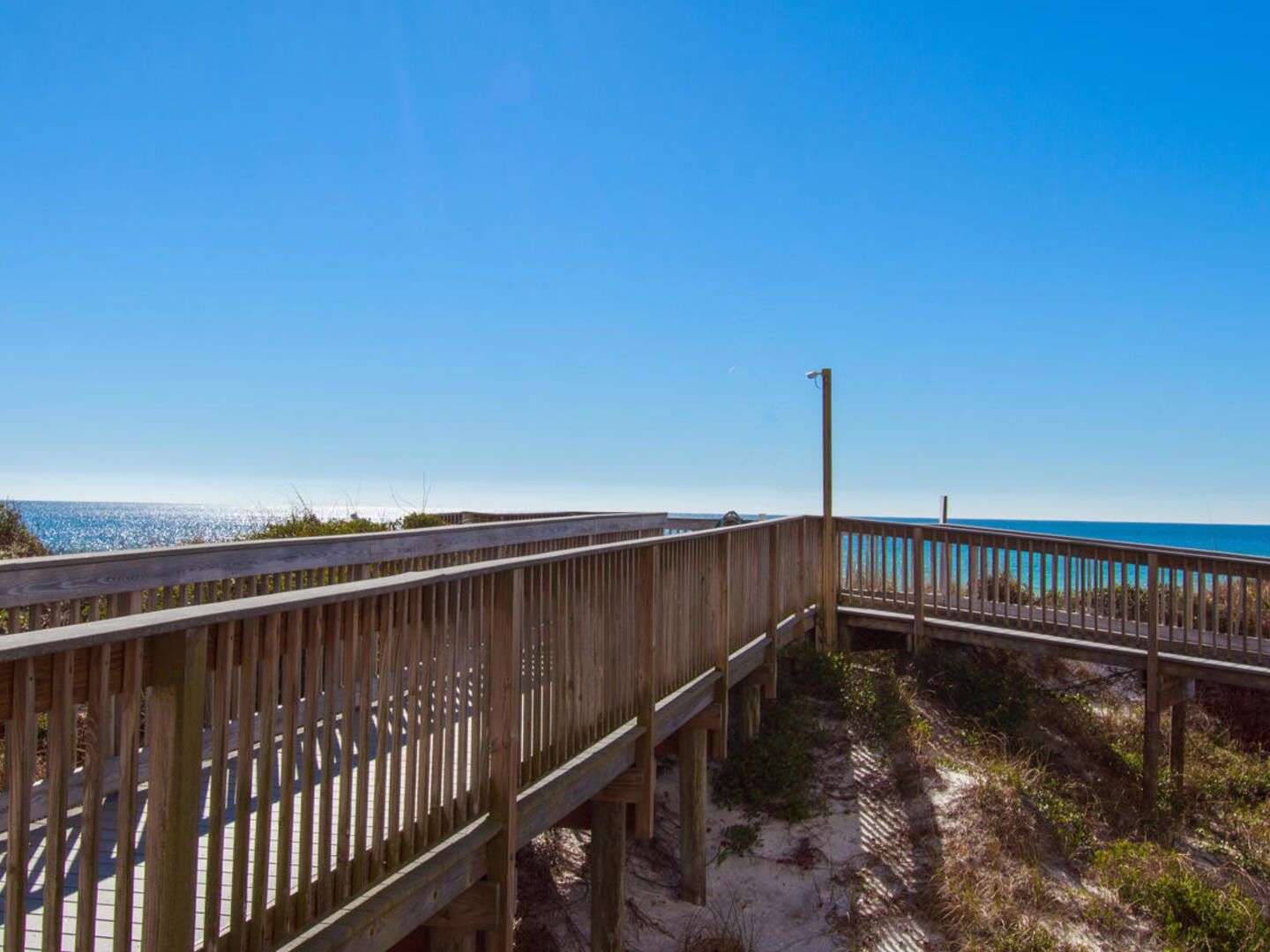 Un paseo marítimo de madera que conduce a una playa con aguas azul cristalino.
