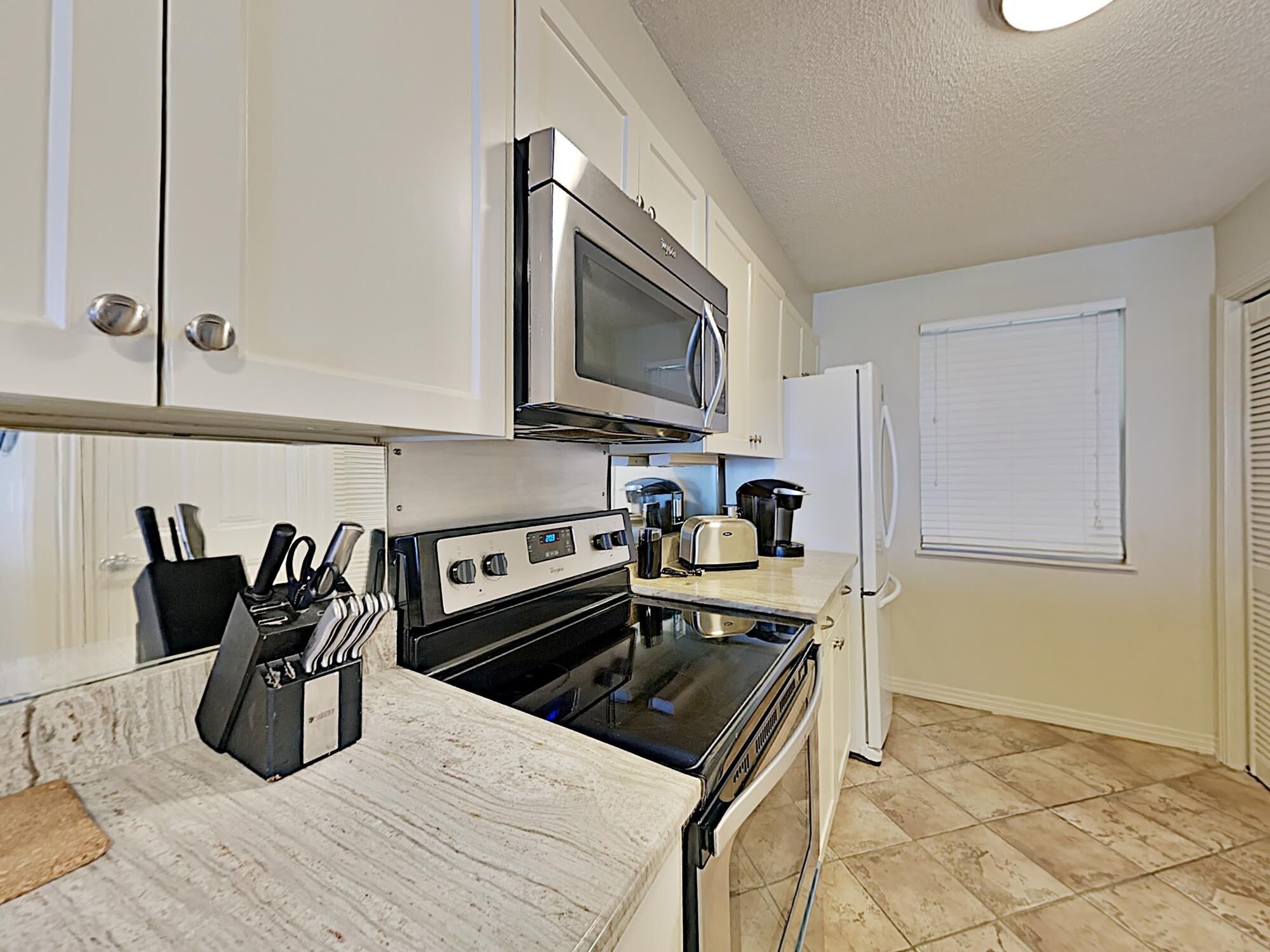 A kitchen with white cabinets, a microwave, a stove, and a refrigerator.