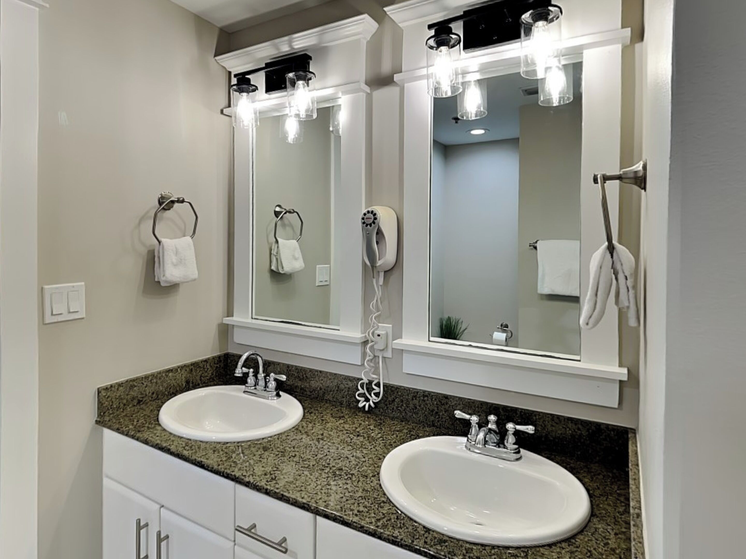 A bathroom with two sinks, a mirror, and a towel rack.