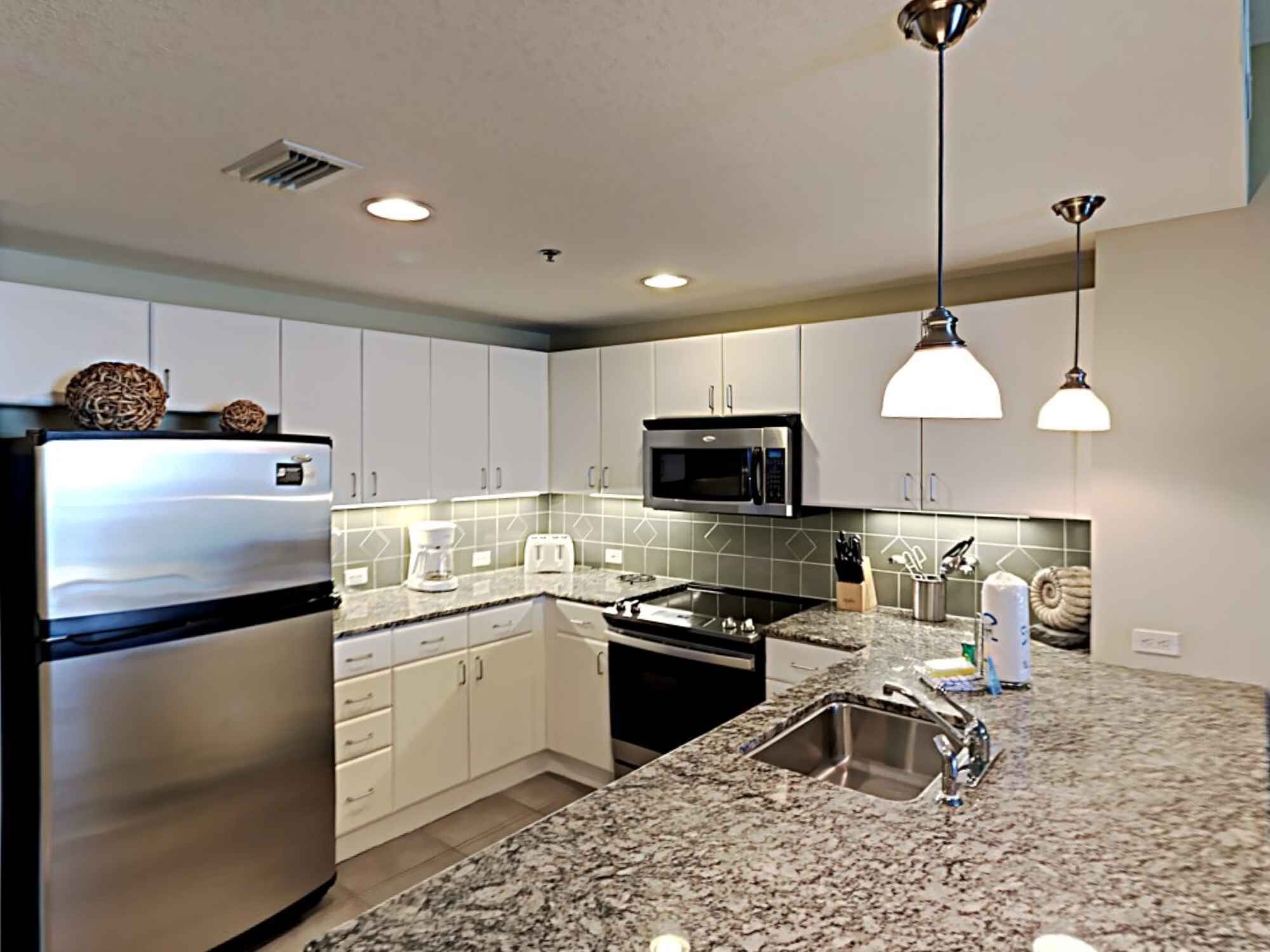 A modern kitchen with stainless steel appliances, granite countertops, and pendant lighting.