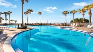 Una piscina azul cristalina rodeada de palmeras y sillas de descanso.