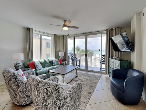 A spacious living room with a sofa set, a coffee table, and a TV mounted on the wall.