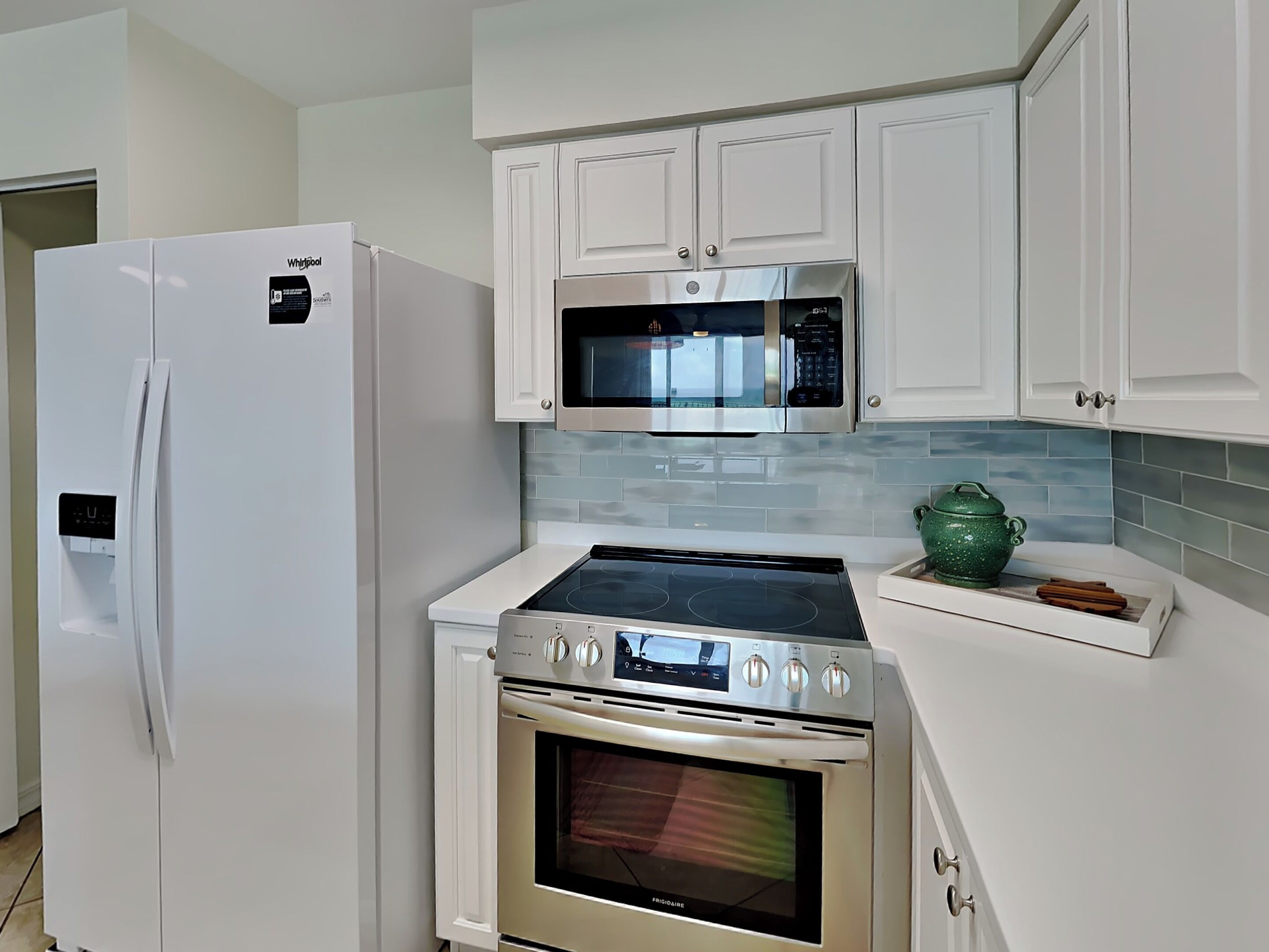 Une cuisine moderne avec des meubles blancs, un réfrigérateur en acier inoxydable, un four à micro-ondes, une plaque de cuisson à induction et un four traditionnel.