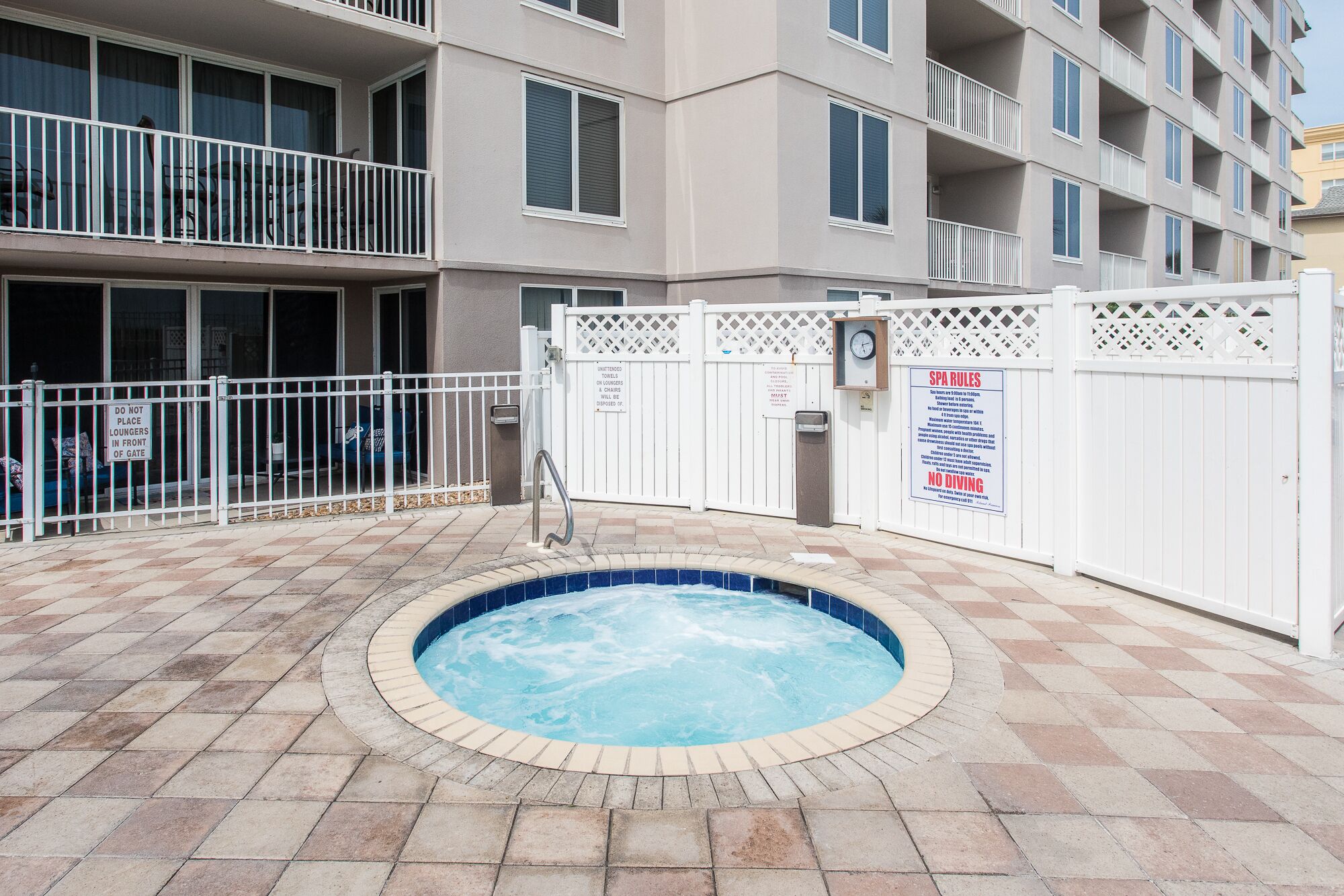 A swimming pool surrounded by a white fence with a sign indicating spa rules.
