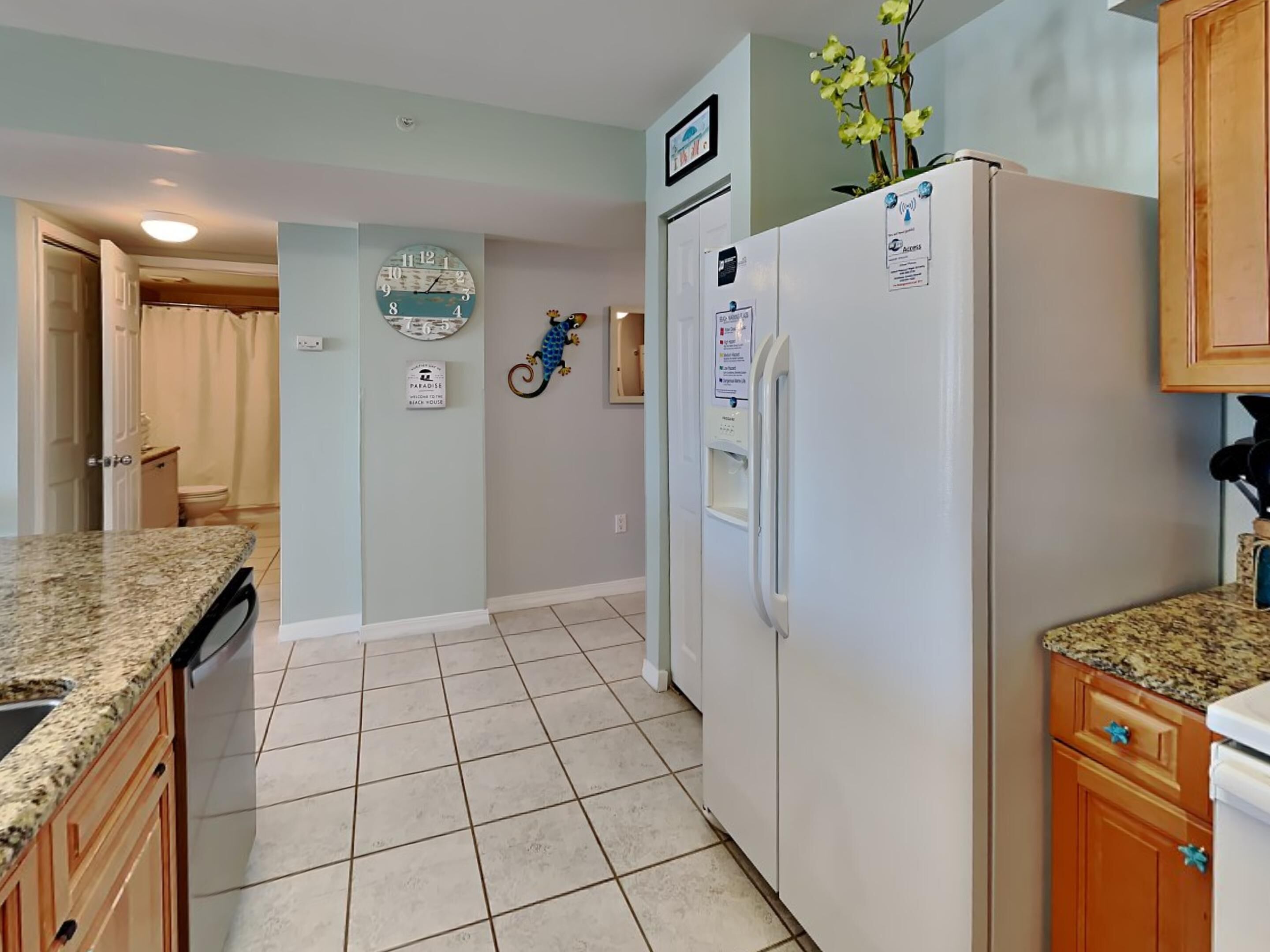 Una cocina con un refrigerador, un reloj y un letrero de bienvenida.
