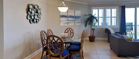 A dining area with a chandelier, a dining table with chairs, and a large potted plant.
