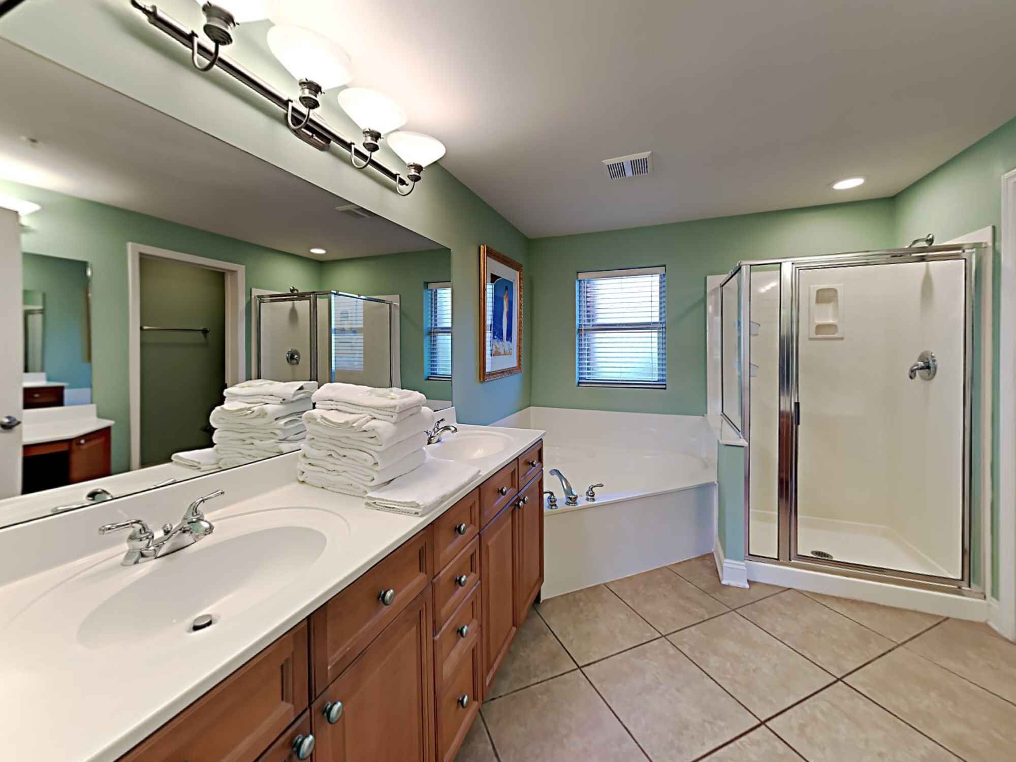 Une salle de bain avec deux lavabos, une baignoire, une douche et un grand miroir.