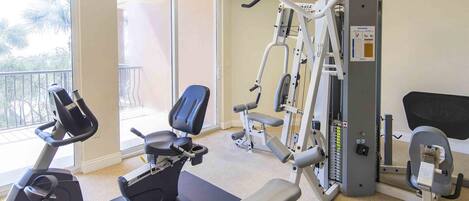 A gym with cardio equipment, weight machines, and a bench.