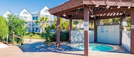 Área externa coberta com piscina, pérgola de madeira e portão.
